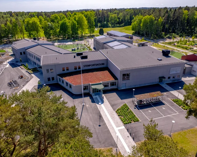 En flygbild av en stor skolbyggnad omgiven av träd.