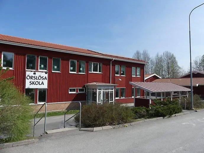 Örslösas röda skola med namnet i svart text på vit bakgrund